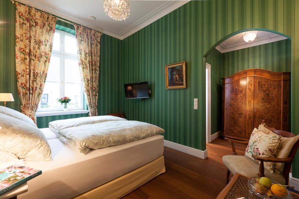 ボホルトにあるRooms GUT HEIDEFELDの緑の壁のベッドルーム1室、ベッド1台、椅子1脚が備わります。