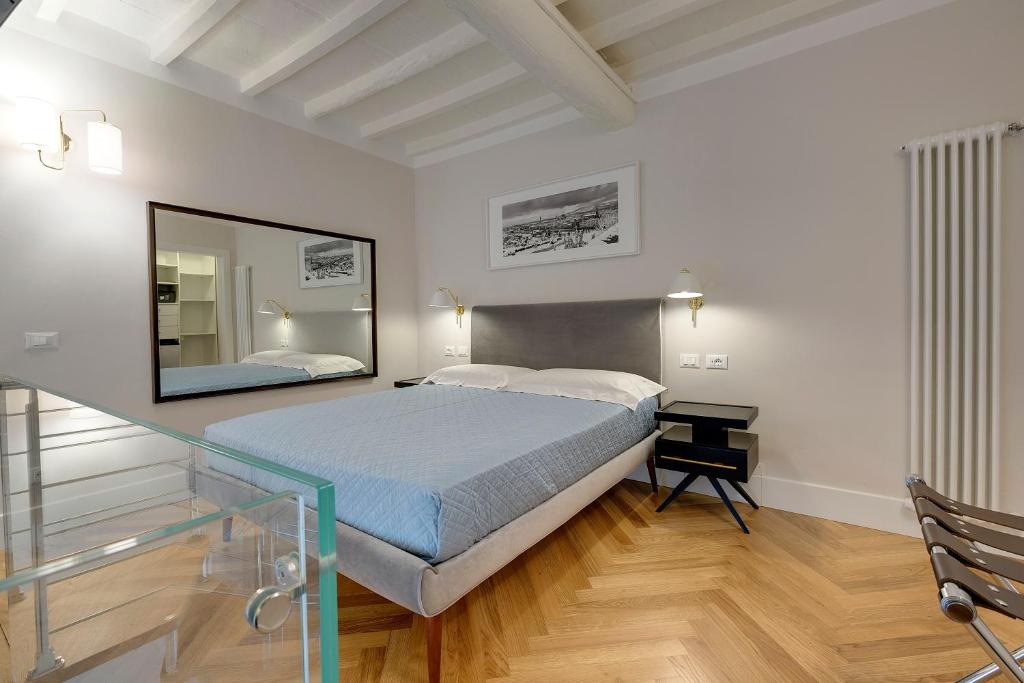 ein Schlafzimmer mit einem großen Bett und einem Spiegel in der Unterkunft TAILOR HOUSE B&B in Florenz