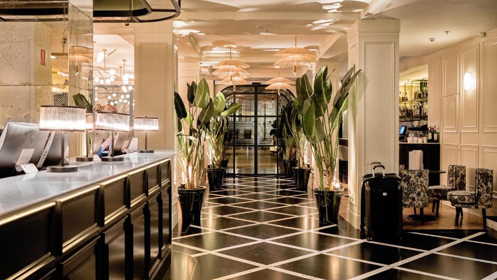 a lobby with a bar with plants on the floor at Hotel Regina in Madrid