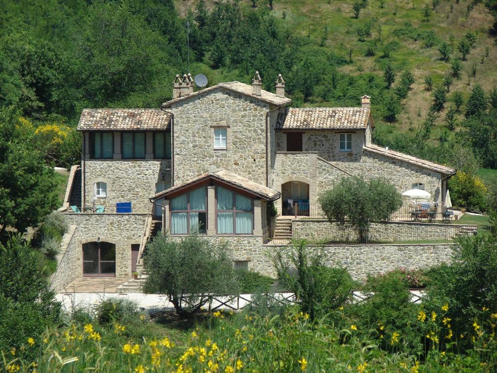 a large stone house in the middle of a field at Casale Merlino in Assisi
