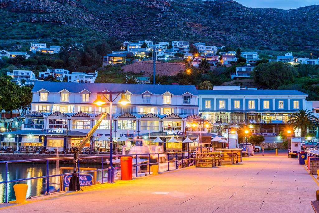 a resort on the water at night at Simon's Town Quayside Hotel in Simonʼs Town