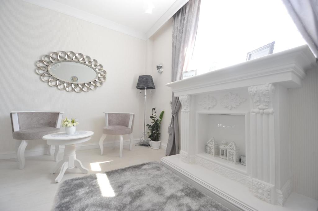 een witte woonkamer met een open haard en een spiegel bij Margot Luxury Studio in Belgrado