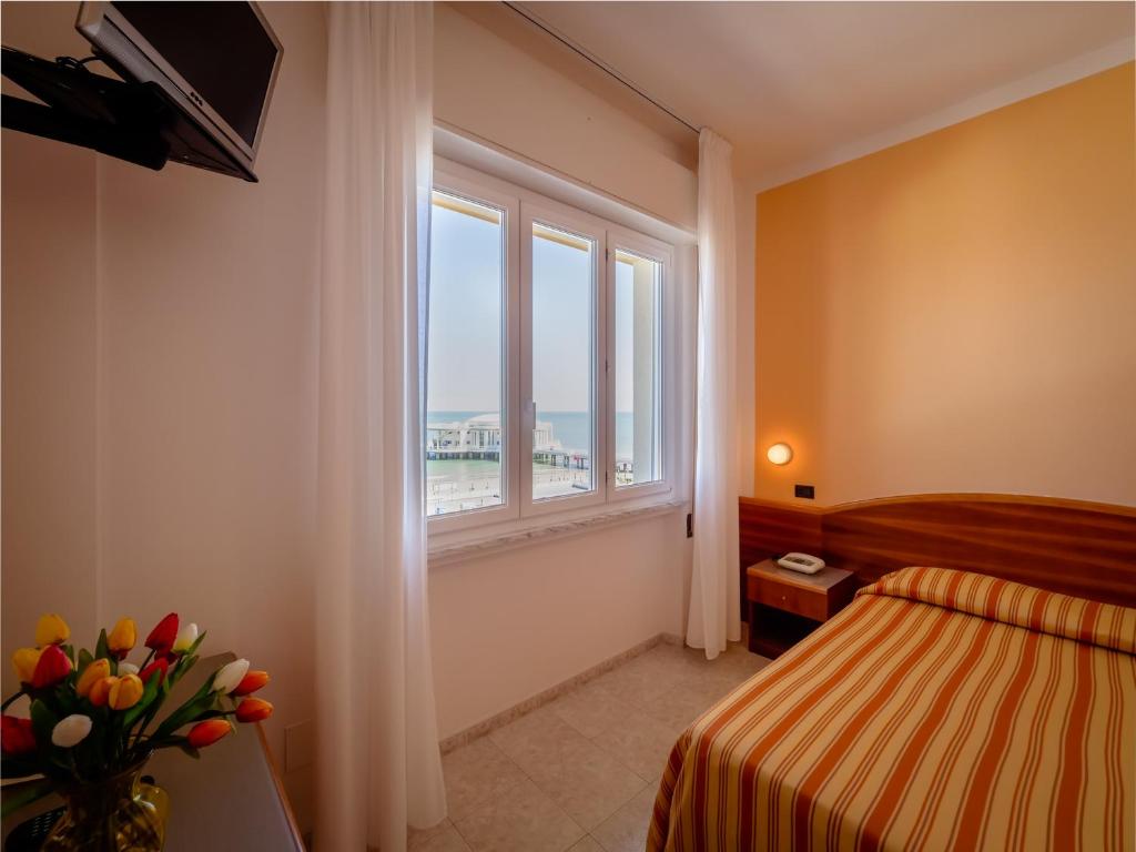 ein Hotelzimmer mit einem Bett und einem Fenster in der Unterkunft Hotel de la Ville in Senigallia