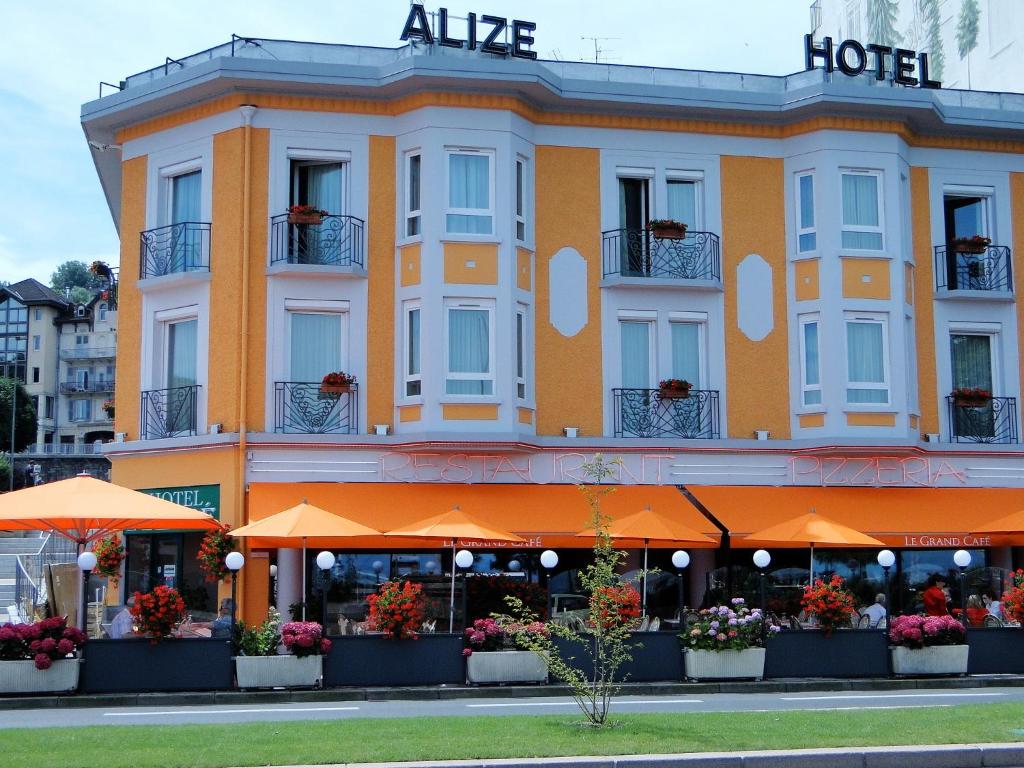 エヴィアン・レ・バンにあるThe Originals Boutique, Hôtel Alizé, Évian-les-Bains (Inter-Hotel)のオレンジの傘を用いたアルダホテルのある建物