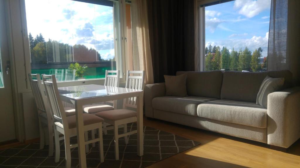uma sala de estar com um sofá, uma mesa e cadeiras em Pähkinäpuisto Apartments em Tampere