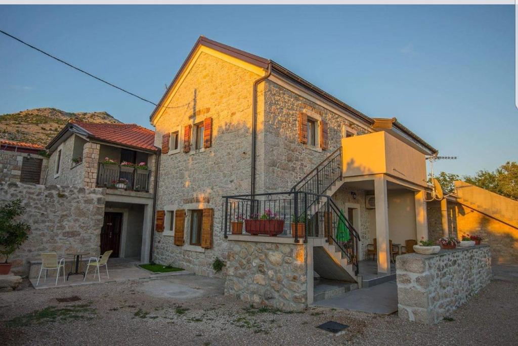 ein Steinhaus mit einer Treppe und einem Balkon in der Unterkunft Apartments Punta in Starigrad-Paklenica