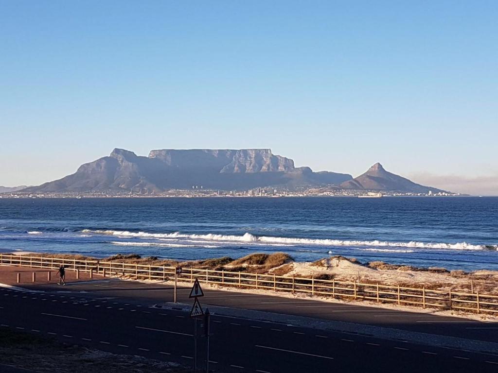 a beach with a view of the ocean and mountains at Blouberg Luxury Beachfront Apartment in Bloubergstrand