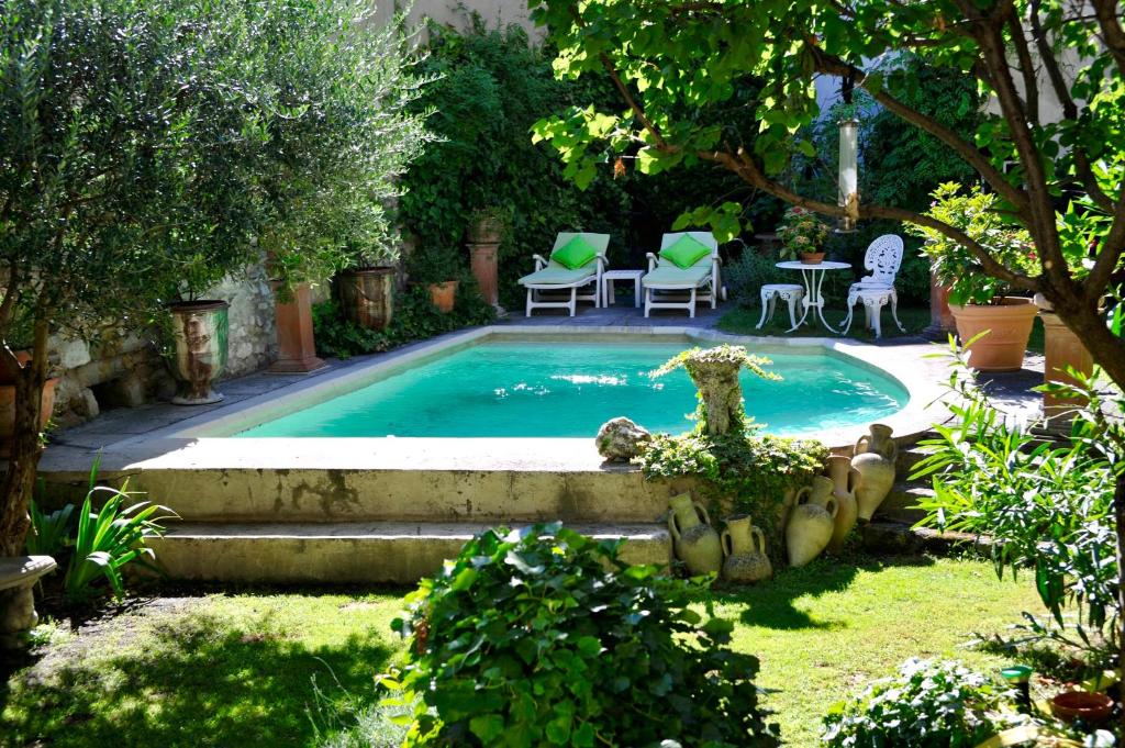 ein Swimmingpool in einem Garten mit Tisch und Stühlen in der Unterkunft Les Saisons in Villeneuve-lès-Avignon