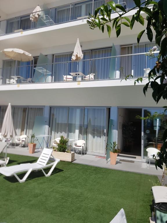 a lawn in front of a building with two lawn chairs at Casa Praia Mar in Salema