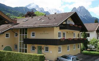 un gran edificio amarillo con un coche aparcado delante de él en Alpenhof Garnihotel & Ferienwohnungen, en Garmisch-Partenkirchen