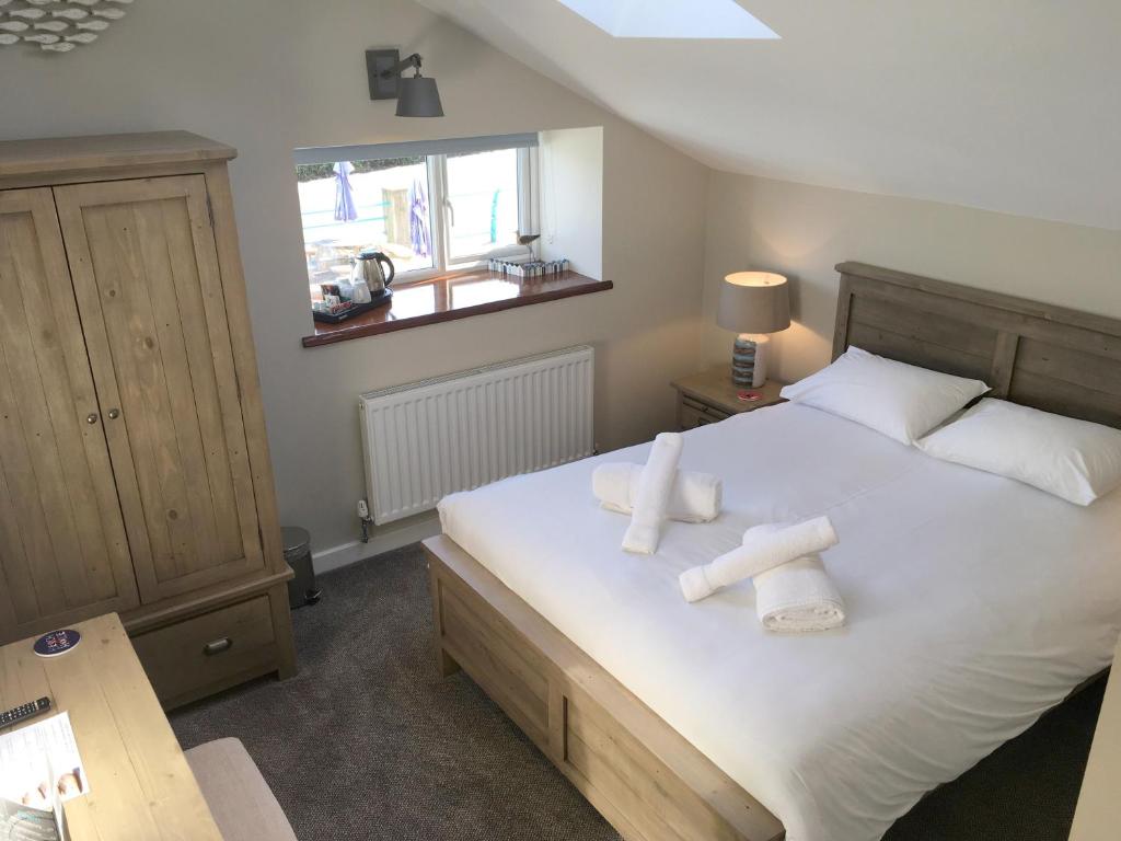 a bedroom with a large white bed with towels on it at The Waterfront Inn in Westward Ho