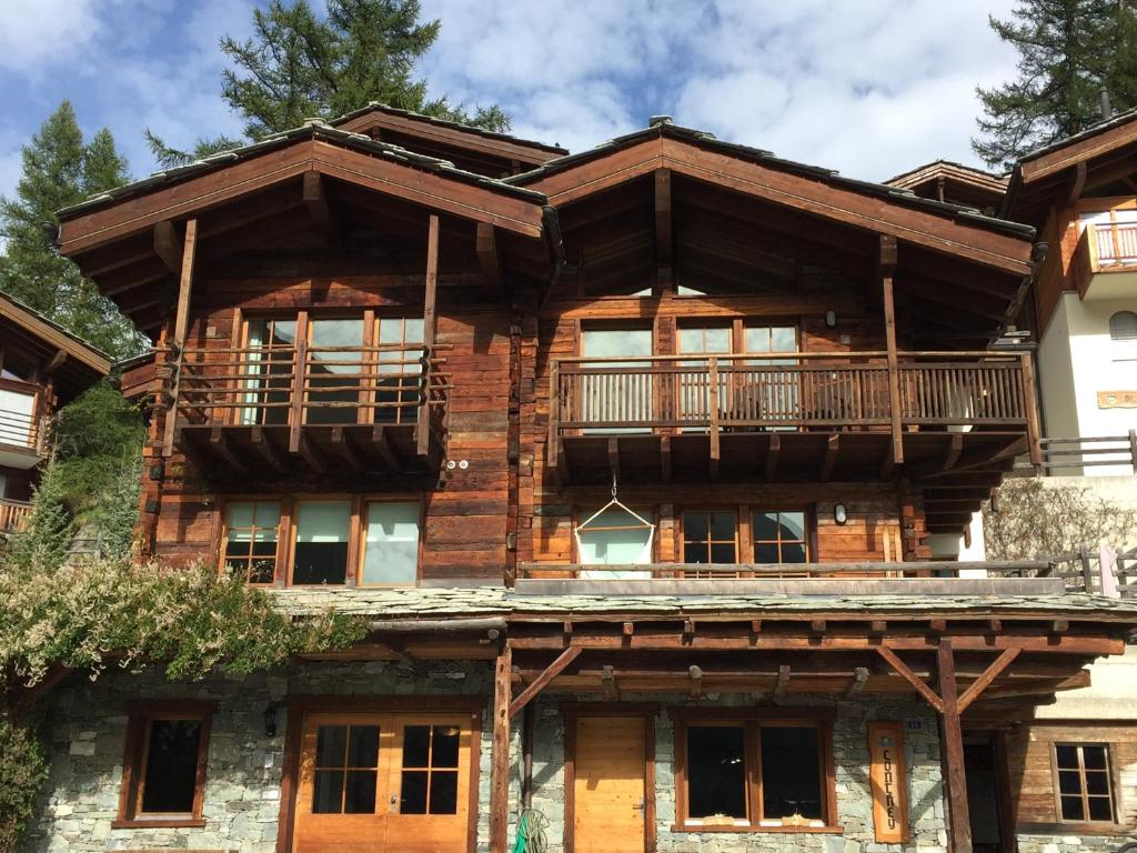 a large wooden house with a balcony on top at Chalet Conthey in Zermatt