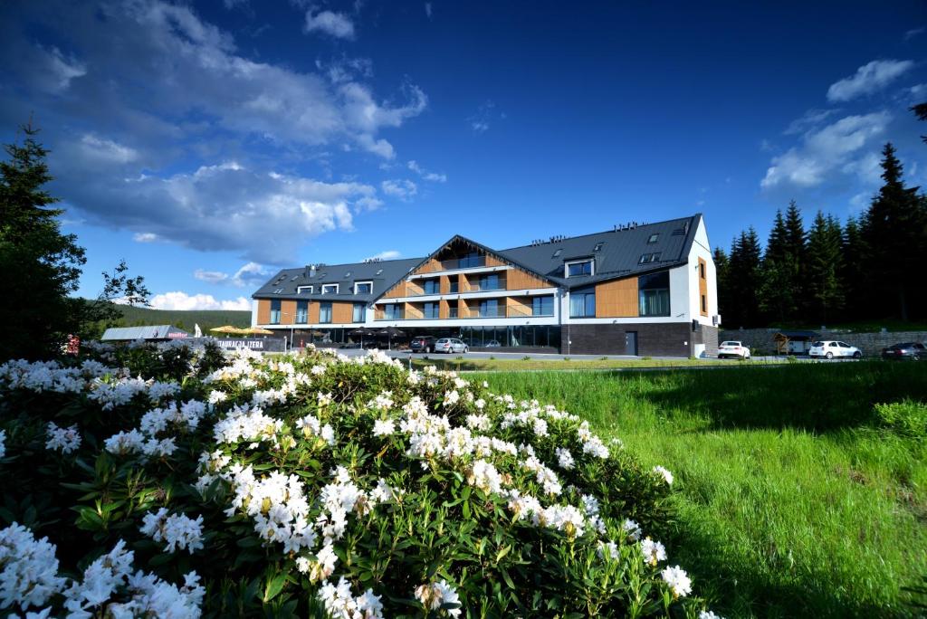 un grande edificio con un campo di fiori di Hotel Jakuszyce Sport & Spa a Szklarska Poręba