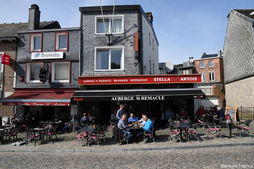 un grupo de personas sentadas en las mesas fuera de un restaurante en L'Auberge Saint Remacle, en Stavelot