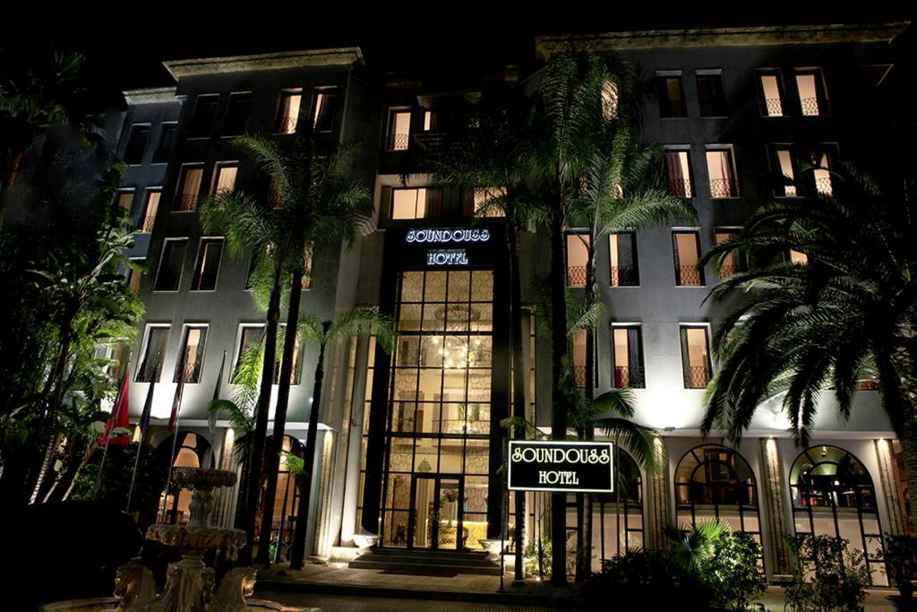 a building with palm trees in front of it at night at Soundouss Hotel in Rabat