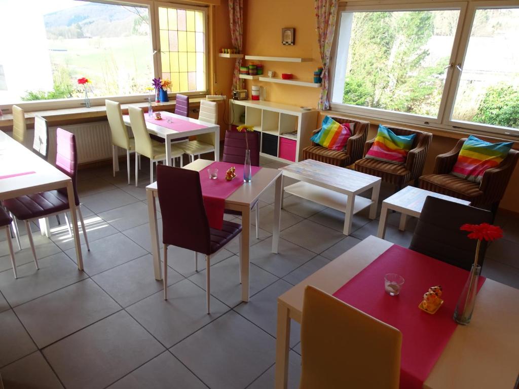 un comedor con mesas, sillas y ventanas en Familie Hotel Kameleon, en Olsberg