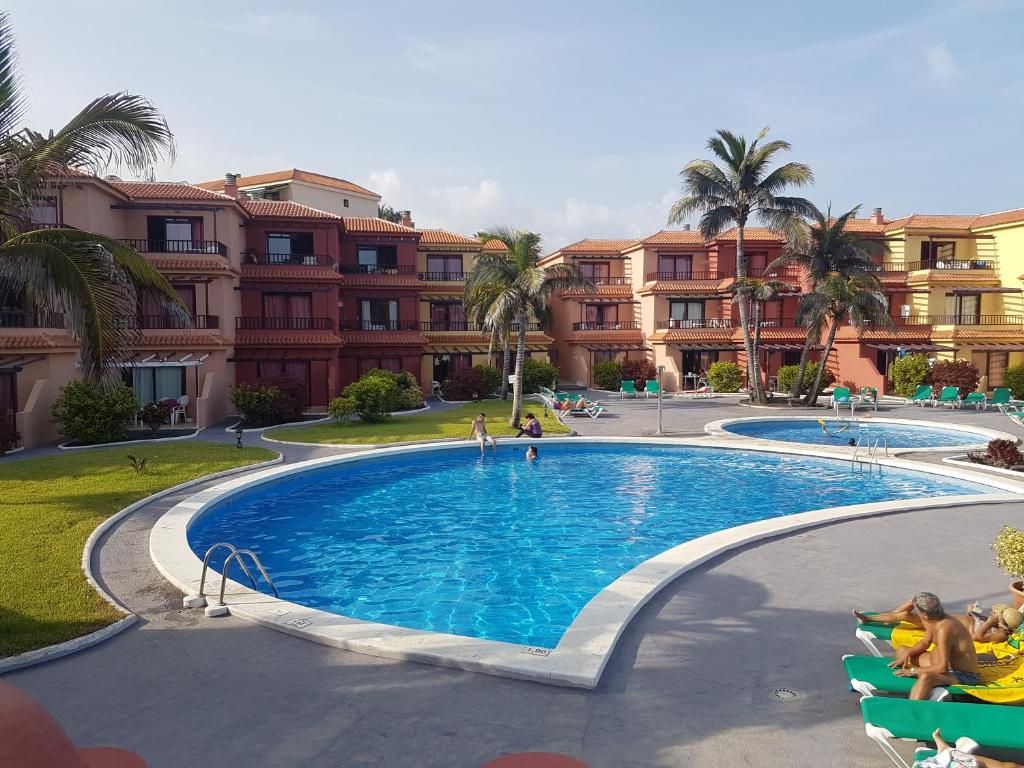 uma piscina num resort com palmeiras e edifícios em RELAX ISLEÑO em Breña Baja