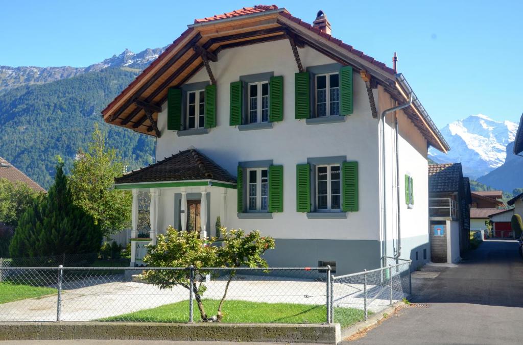 ein Haus mit grünen Rollläden auf einem Berg in der Unterkunft Jungfrau Family Holiday Home in Matten