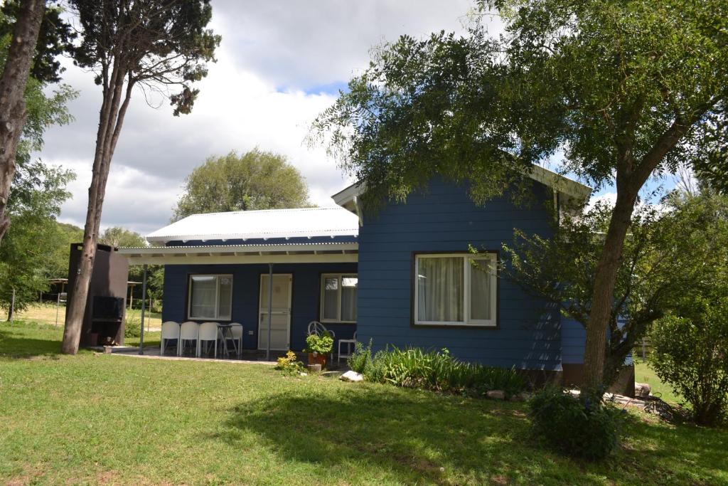 una casa azul con sillas en un patio en Casitas La Invernada en Villa Giardino