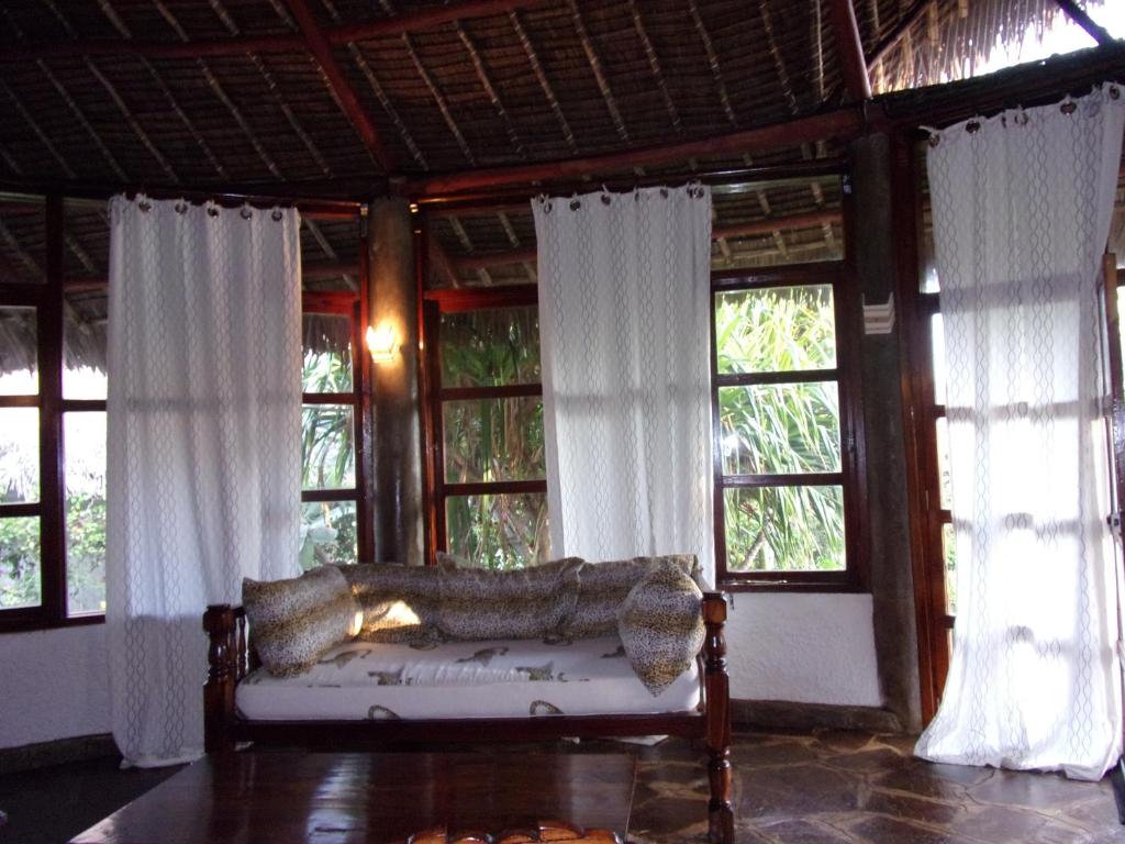 a living room with a couch in front of windows at Red Sunshine Villa B&B in Malindi