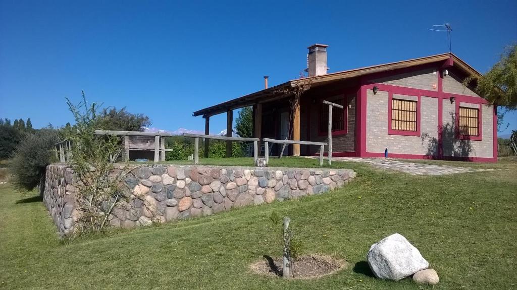 ein Haus mit einer Steinmauer davor in der Unterkunft Cabaña del Alto Tupungato in Tupungato