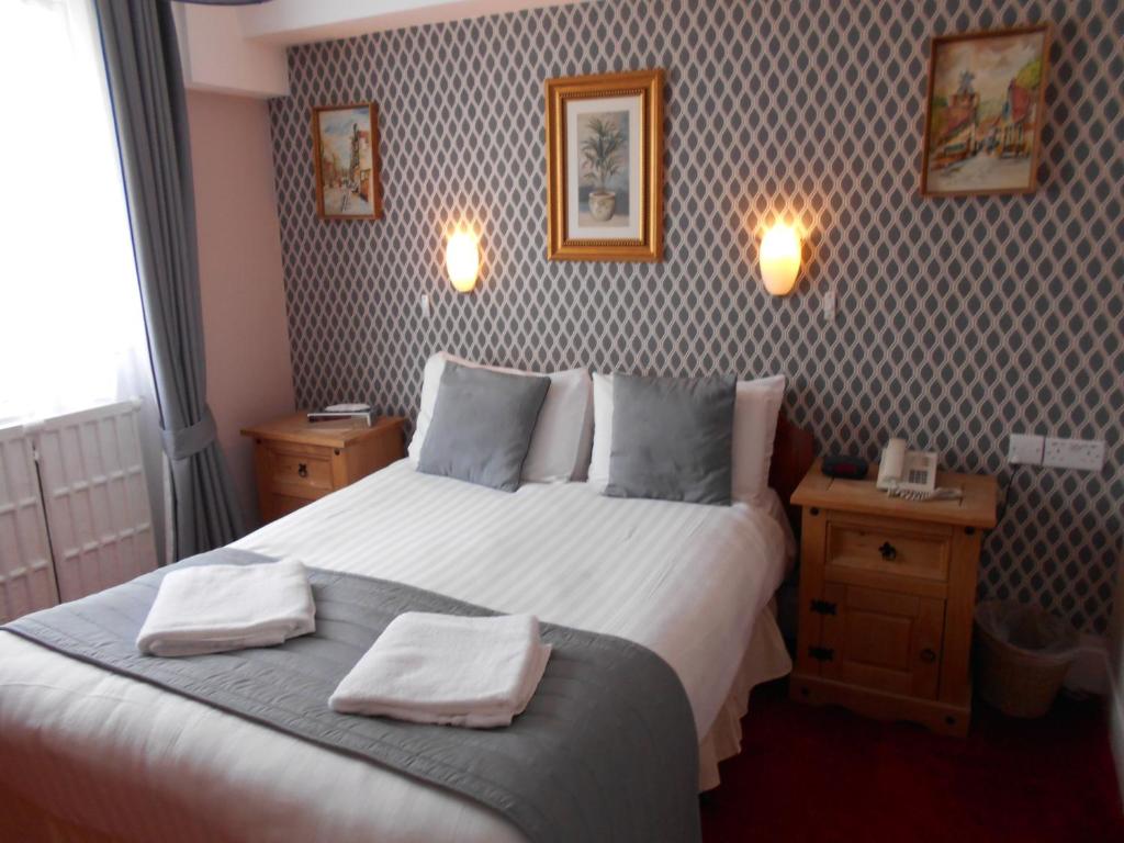 ein Schlafzimmer mit einem großen Bett mit zwei Handtüchern darauf in der Unterkunft Parkwood Hotel in London