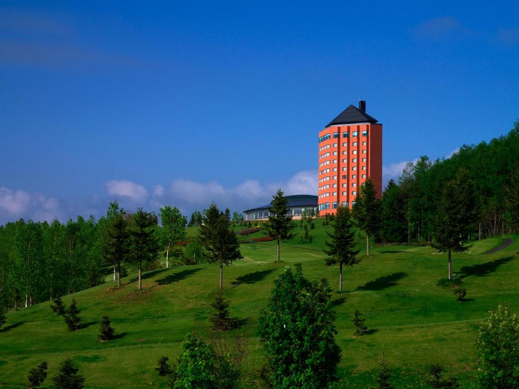 a tall building on top of a green field at Furano Resort Orika in Nakafurano