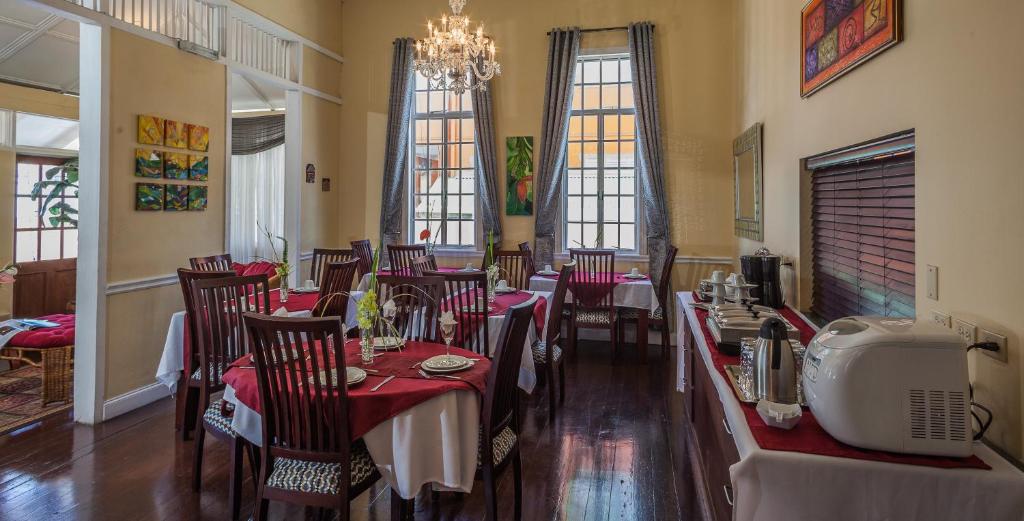 a restaurant with red tables and chairs and a chandelier at Inn at 87 in Port-of-Spain