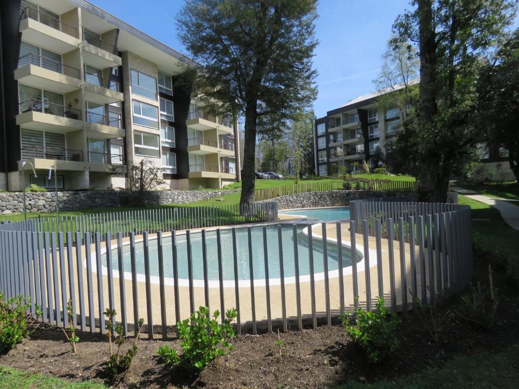 a fence around a swimming pool in front of a building at Parque Payllahue Departamento in Pucón