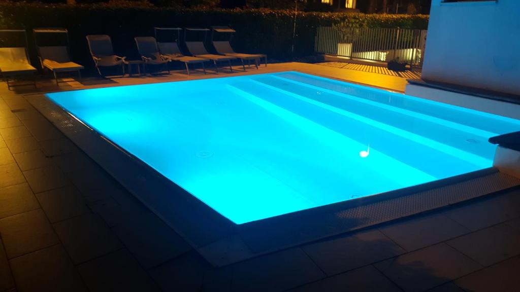 una piscina notturna con illuminazione blu di Sirmione Rosselli Apartments a Sirmione