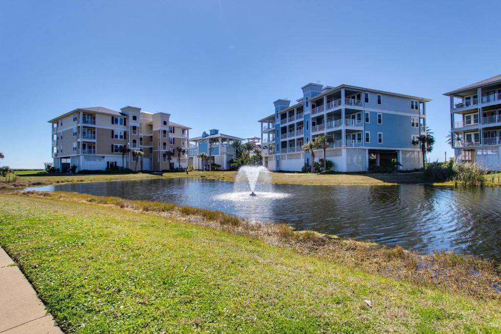 una fuente en un estanque frente a algunos edificios de apartamentos en Point West Resort en Galveston