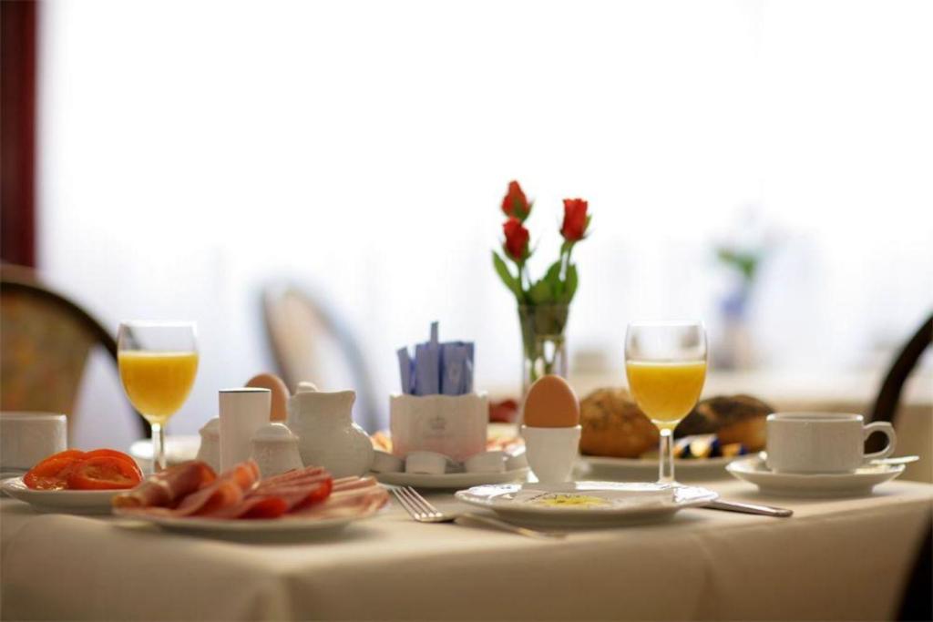 einen Tisch mit Essen und zwei Gläsern Orangensaft in der Unterkunft Hotel Moguntia in Mainz