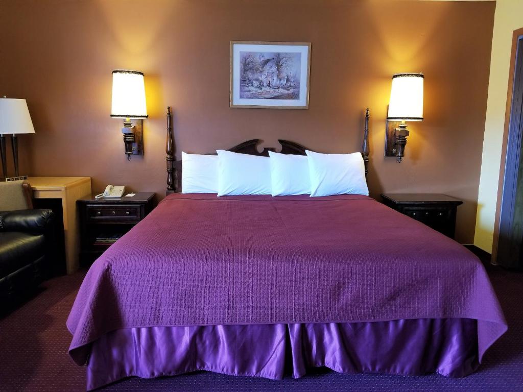 a hotel room with a large bed with a purple bedspread at Regency Inn in Winnemucca