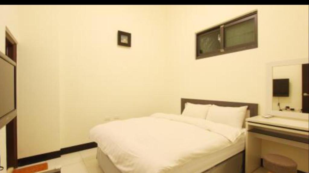 a bedroom with a white bed and a mirror at Kenting Orange Homestay in Hengchun