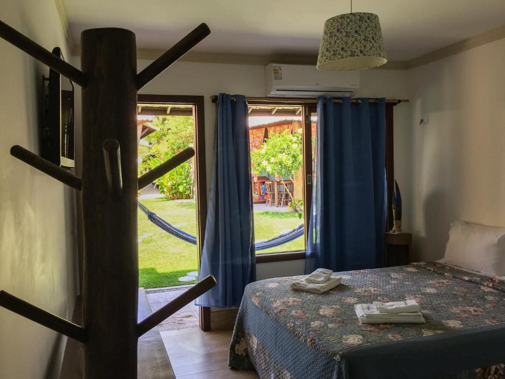 a bedroom with a bed and a window with blue curtains at Pousada Aconchego de Genipabu in Genipabu