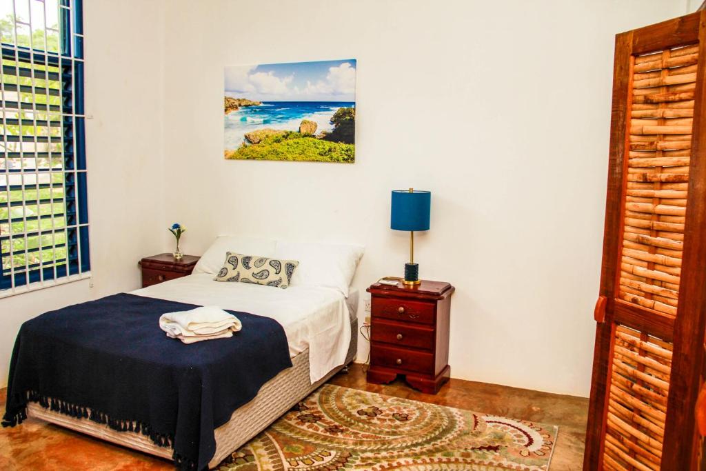 a bedroom with a bed and a table with a lamp at Sunshine Lodge: Your home away from home in Montego Bay