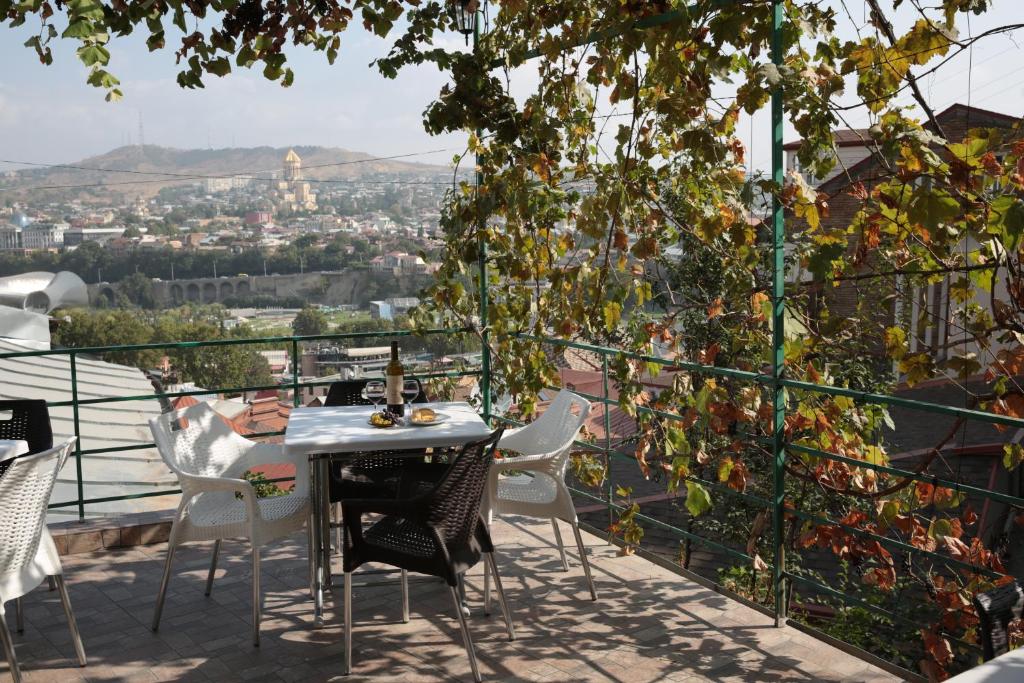 einen Tisch und Stühle auf einem Balkon mit Aussicht in der Unterkunft Cherdachok in Tbilisi City