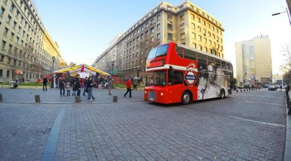 a red double decker bus driving down a city street at Depto. Margarita Zenteno in Santiago