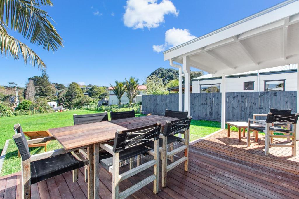 a wooden deck with a wooden table and chairs at The Little Blue Bach in Oneroa Village by Waiheke Unlimited in Oneroa