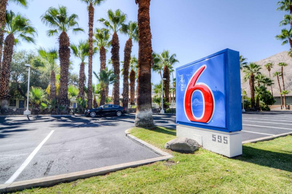 Motel 6-Palm Springs, CA - East - Palm Canyon في بالم سبرينغز: وجود لافتة ببسي في موقف السيارات مع أشجار النخيل