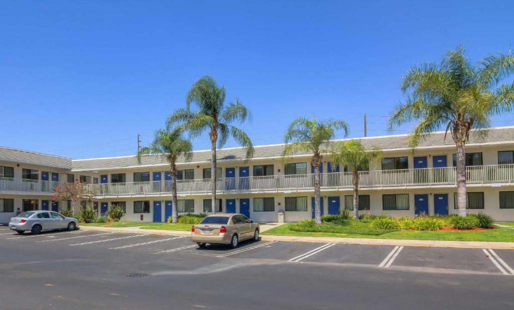 a parking lot in front of a building with palm trees at Vagabond Inn Sylmar in Sylmar