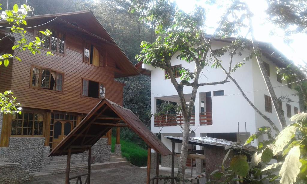 a house with a wooden structure in front of it at Illariy Tampu Ecoalbergue Oxapampa in Oxapampa