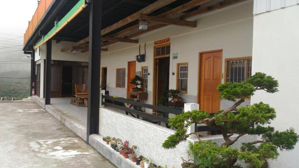 a house with a porch with potted plants on it at Legendary Bed and Breakfast in Fenqihu