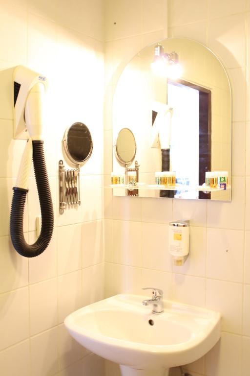 biała łazienka z umywalką i telefonem w obiekcie Hotel Braník w Pradze