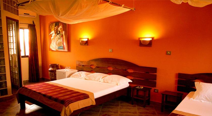 um quarto com uma cama grande e uma parede laranja em Hôtel Serena em Toliara