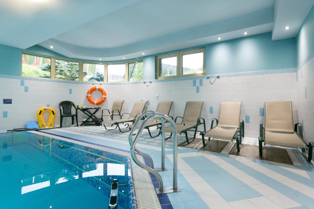 a pool room with chairs and a swimming pool at Apartament Pomarańczowy z basenem i sauną in Kościelisko