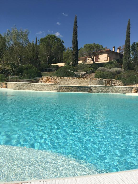 una piscina de agua azul con una casa en el fondo en Bagno Santo Residence en Saturnia