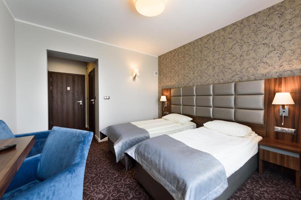 a hotel room with two beds and a blue couch at Hotel Nowy Dwór in Trzebnica
