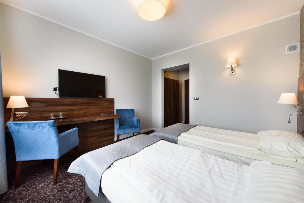 a hotel room with two beds and a desk and a television at Hotel Nowy Dwór in Trzebnica