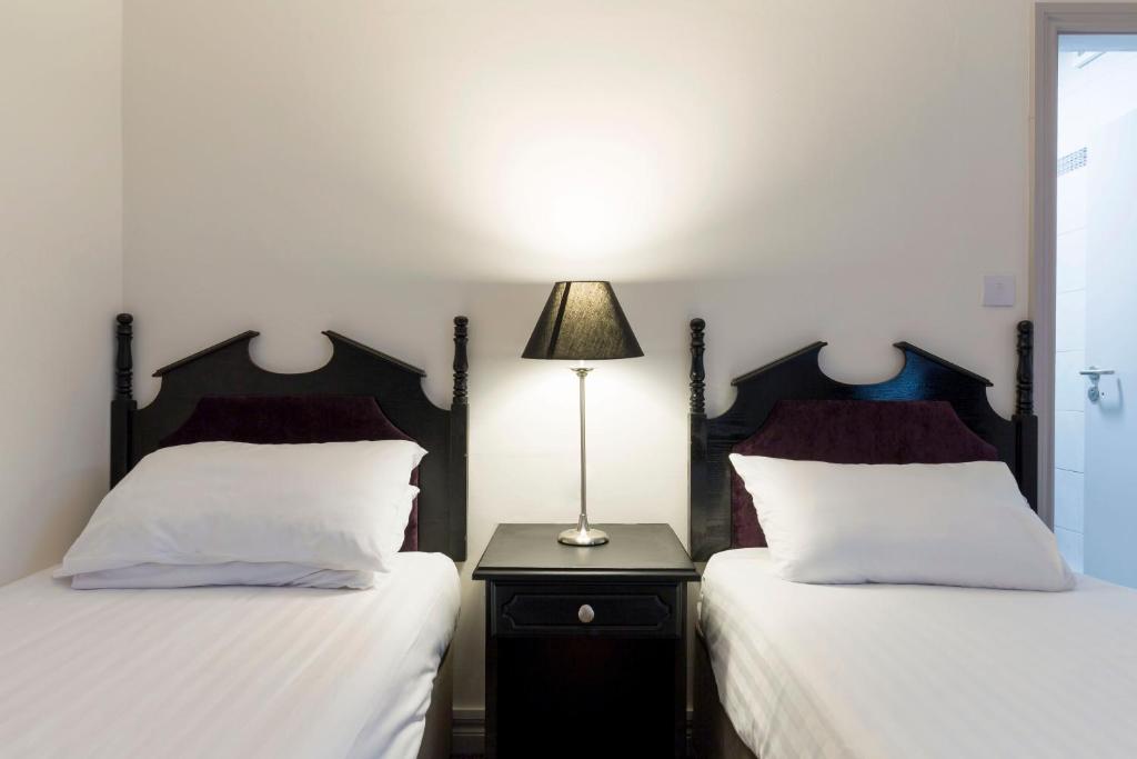 a bedroom with two beds and a lamp on a night stand at Ivy Tower Hotel in Castlebar
